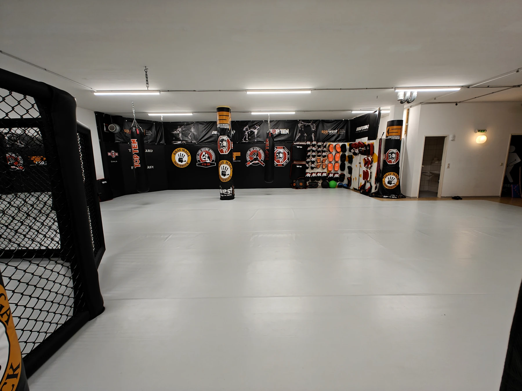 Offene MMA IBK Mattenfläche mit Cage und Ausrüstung