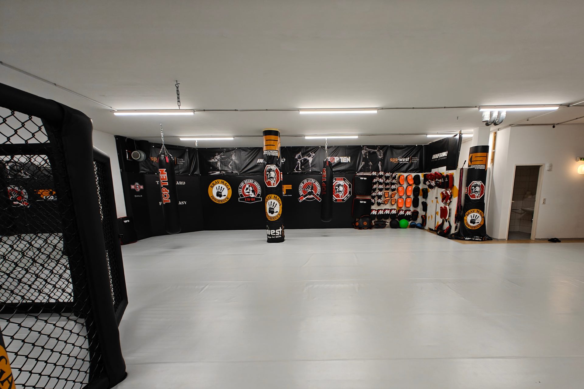 MMA IBK Trainingsfläche mit Cage, Boxsäcken und Disziplin-Wandbannern